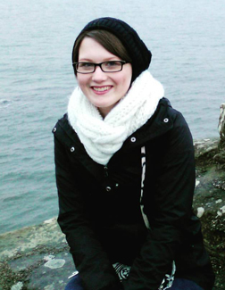 Photo of Jessica Hauger wearing a jacket and posing near the beach.