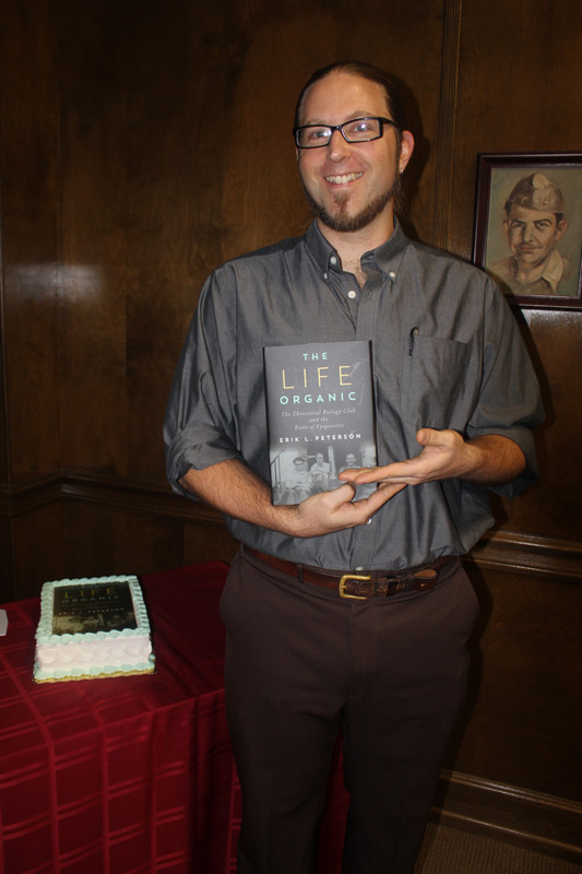Photograph of Dr. Peterson poses with his book in hand.