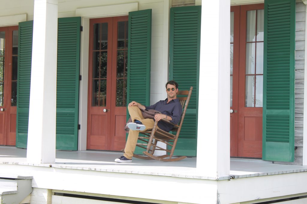 This is an image showing Noah Wylie sitting on a porch.