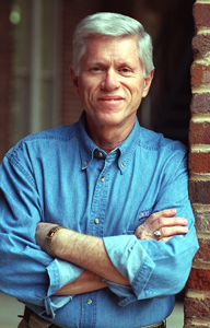 This image shows Howard Jones with his arms crossed, leaning against a brick wall. 