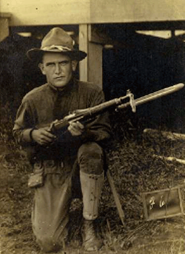 This image shows Don Williams, an Alabama soldier killed in World War I, in uniform, kneeling, holding a 1903 Springfield Rifle with bayonet attached.