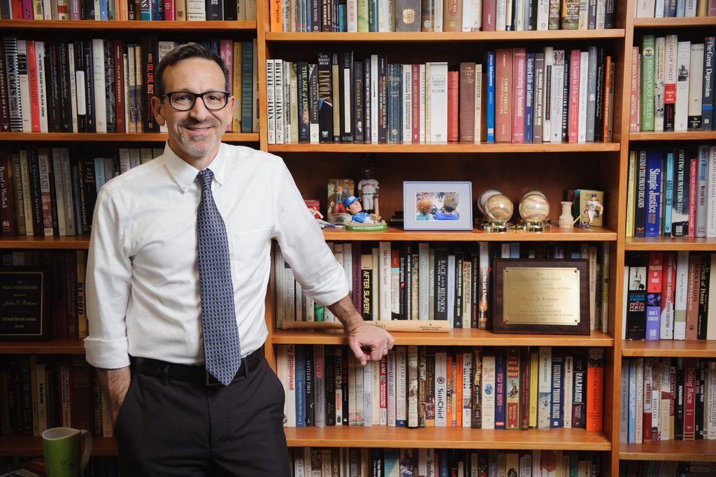 Josh Rothman standing in front of a bookshelf.
