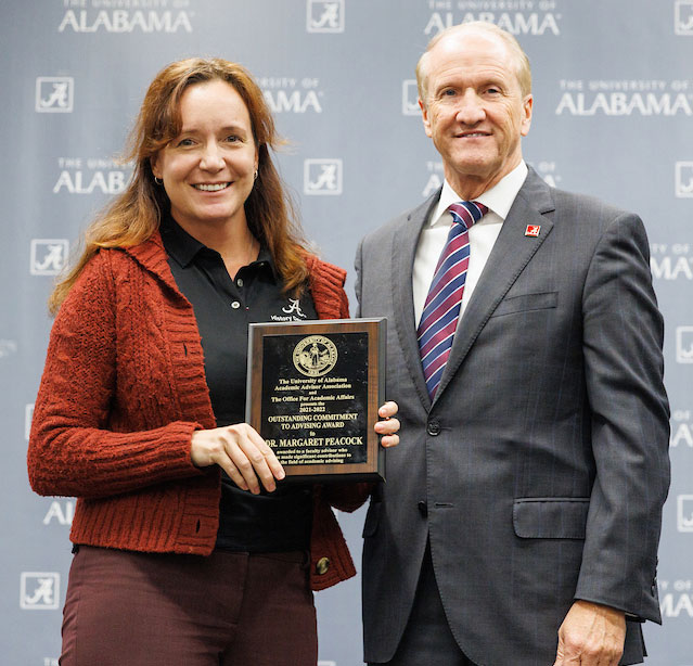 Margaret Peacock holding a plaque recognizing her for this award, accompanied by President Stuart Bell