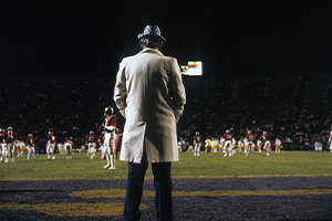 Paul Bryant standing on the sideline of a football game.