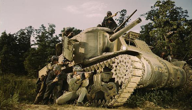 soldiers taking cover behind a tank