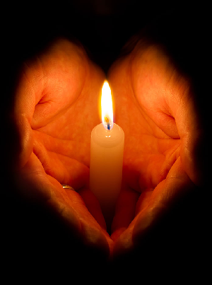 Two hands holding a lit candle.