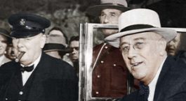Colorized phot of FDR getting out of a car and being greeted by WInston Churchill.