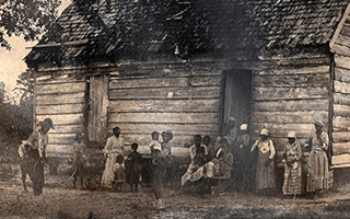 An enslaved family posed outside a cabin.